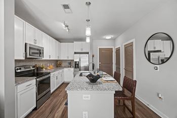 A modern kitchen with white cabinets and a granite countertop at 1010 Dilworth Apartments, Charlotte, NC